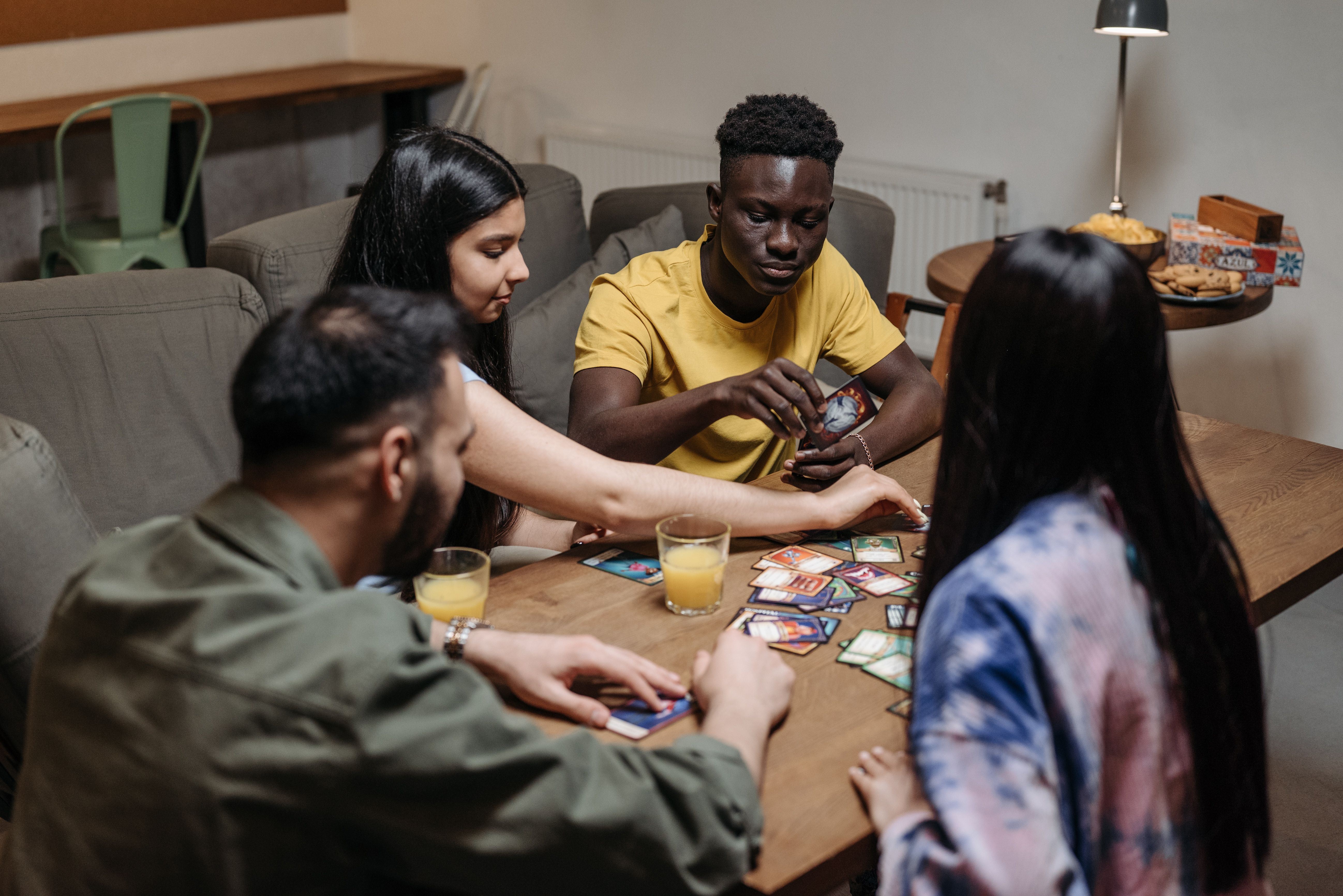 Friends playing a card game together — educational board games for adults that teach real skills