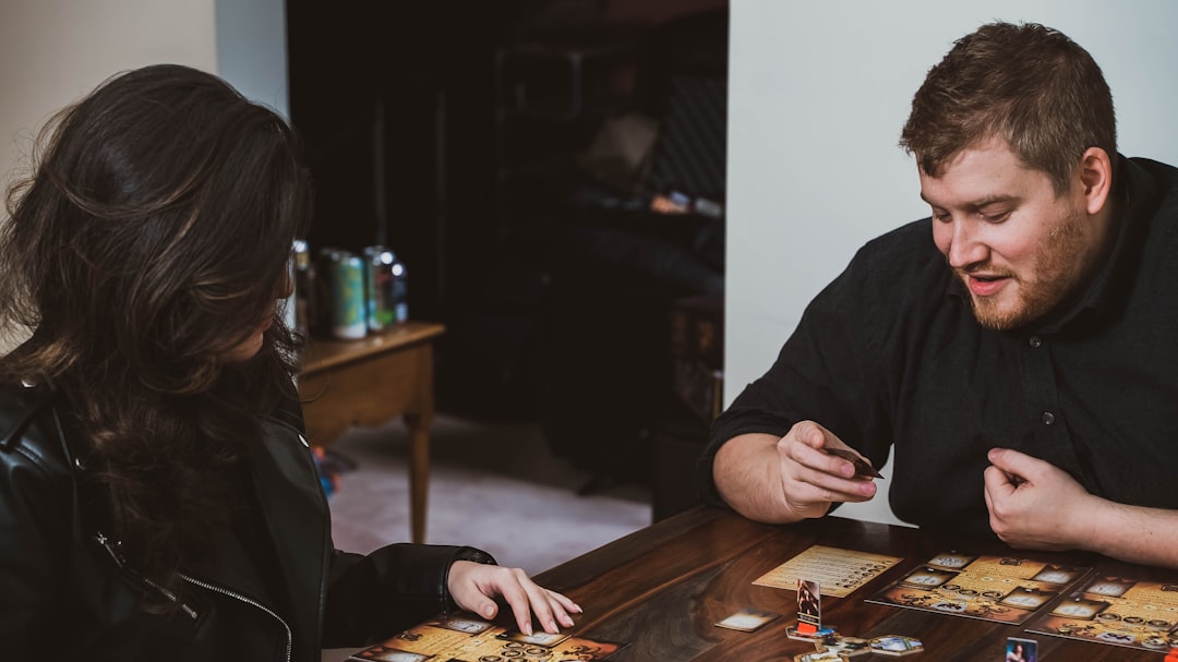 Someone explaining board game rules to friends gathered around a table, pointing at the game board