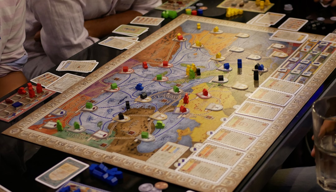 Three people playing a strategy board game together around a table