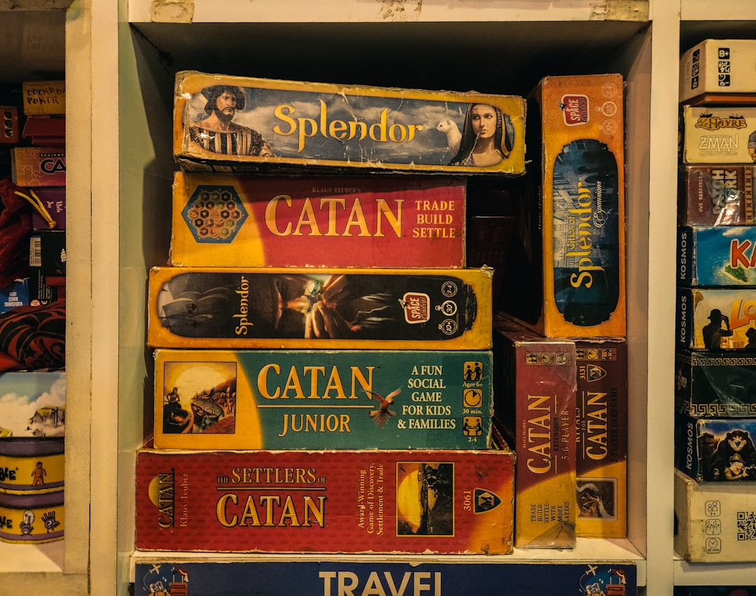 Stack of complex strategy board games including Splendor and Catan on a shelf