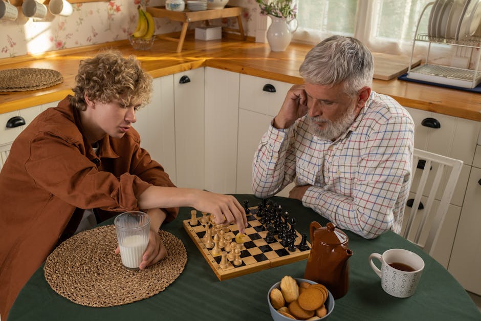 Grandfather and grandson engaged in an intense chess game in a warm kitchen setting.