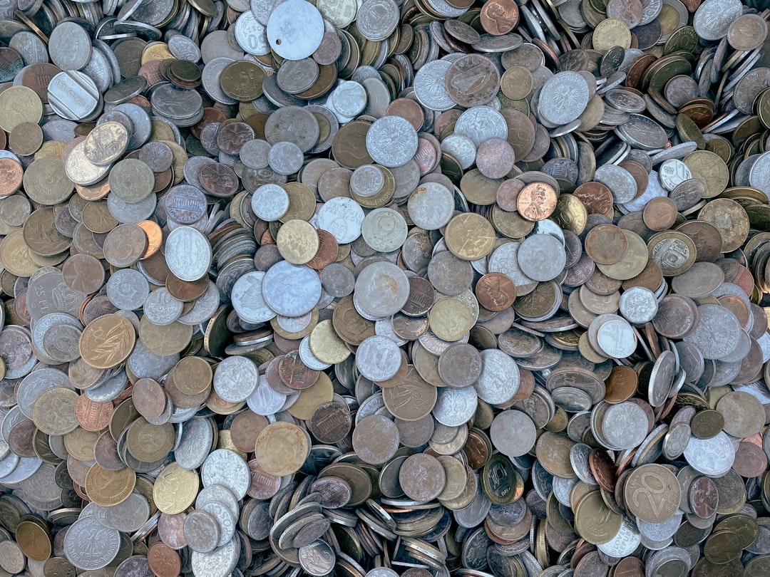 A pile of coins and game tokens on a table, representing the resource management theme of economic board games.
