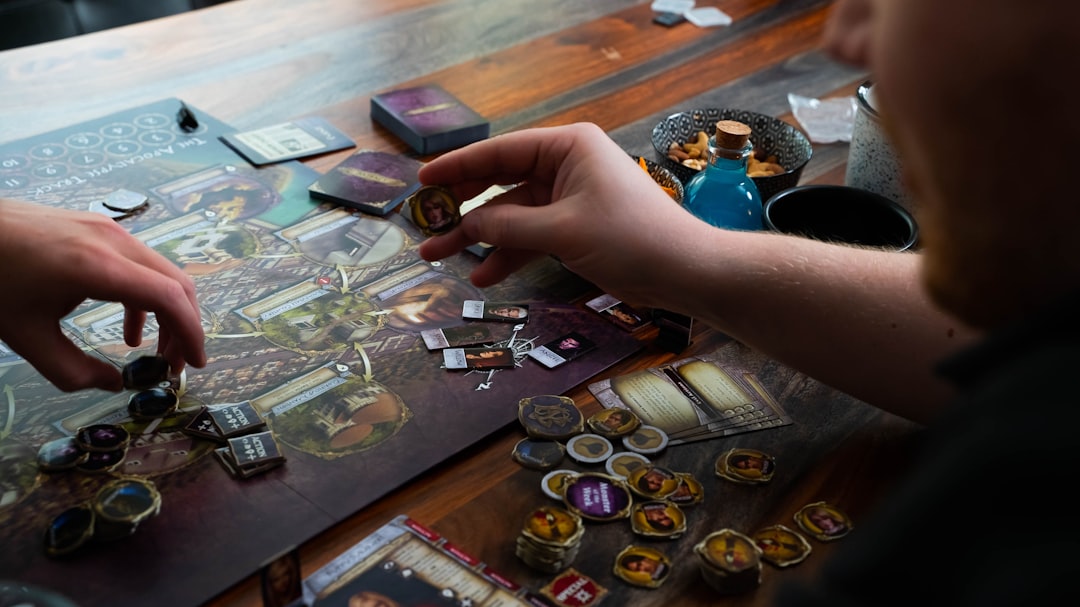 Close-up of players setting up a simple board game with cards and tokens on a wooden table.